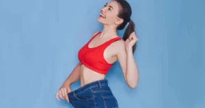 Smiling woman showing loose jeans after weight loss, representing Medical Weight Loss in Sanford, FL